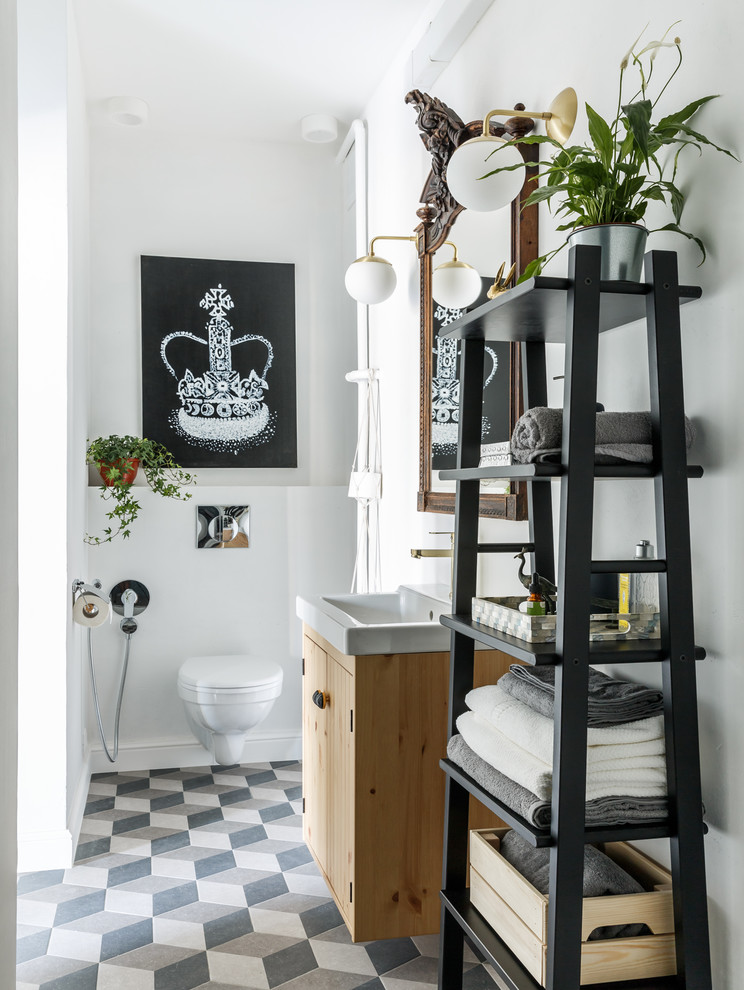 モスクワにあるコンテンポラリースタイルのおしゃれなトイレ・洗面所 (フラットパネル扉のキャビネット、淡色木目調キャビネット、壁掛け式トイレ、白い壁、マルチカラーの床) の写真