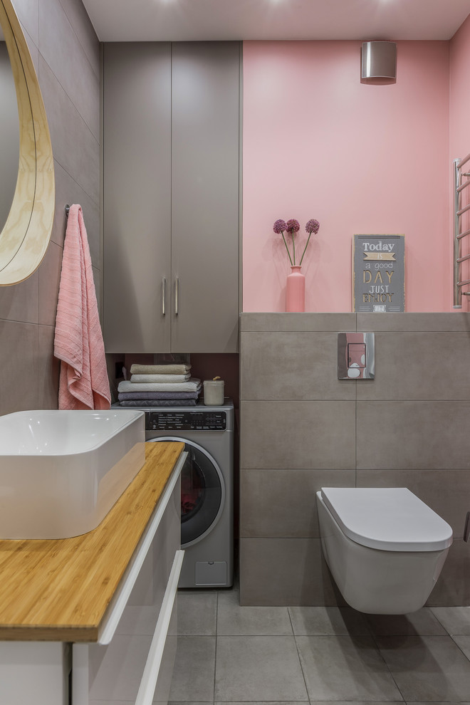 Imagen de aseo contemporáneo con armarios con paneles lisos, paredes rosas, lavabo sobreencimera y suelo gris