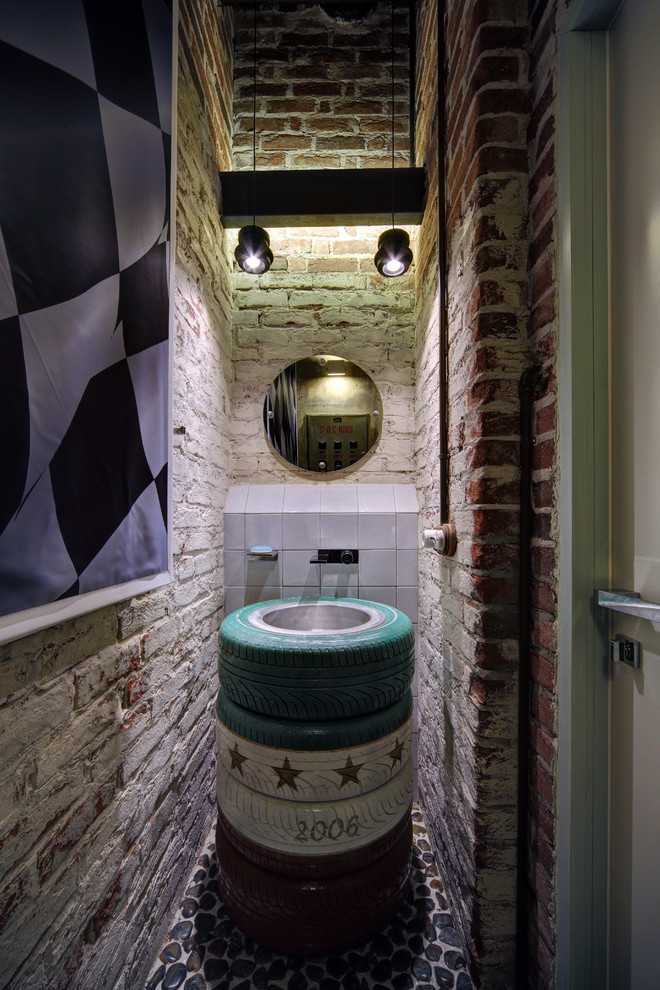 Пример оригинального дизайна: туалет в стиле лофт с разноцветными стенами, полом из галечной плитки, накладной раковиной и разноцветным полом