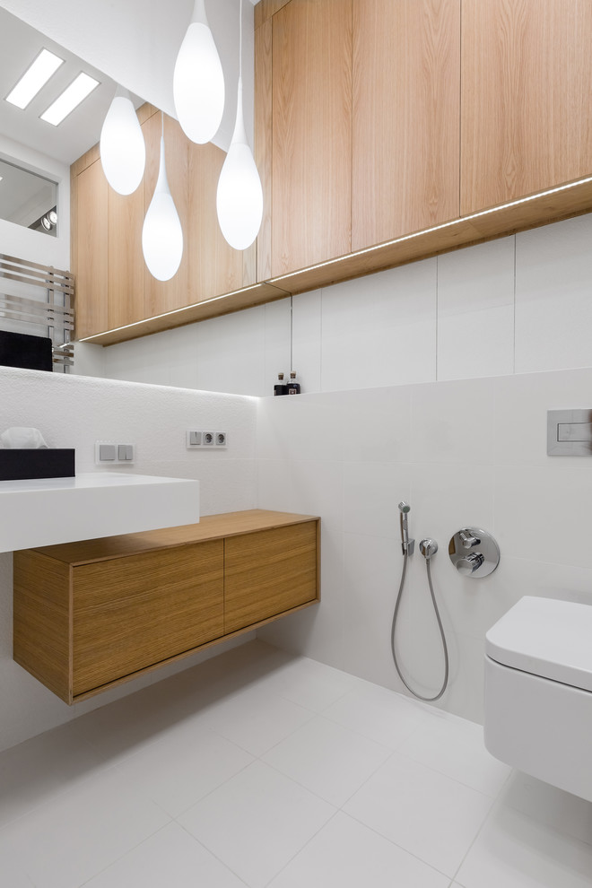 Aménagement d'un WC suspendu contemporain avec un mur gris, un lavabo suspendu et un sol blanc.