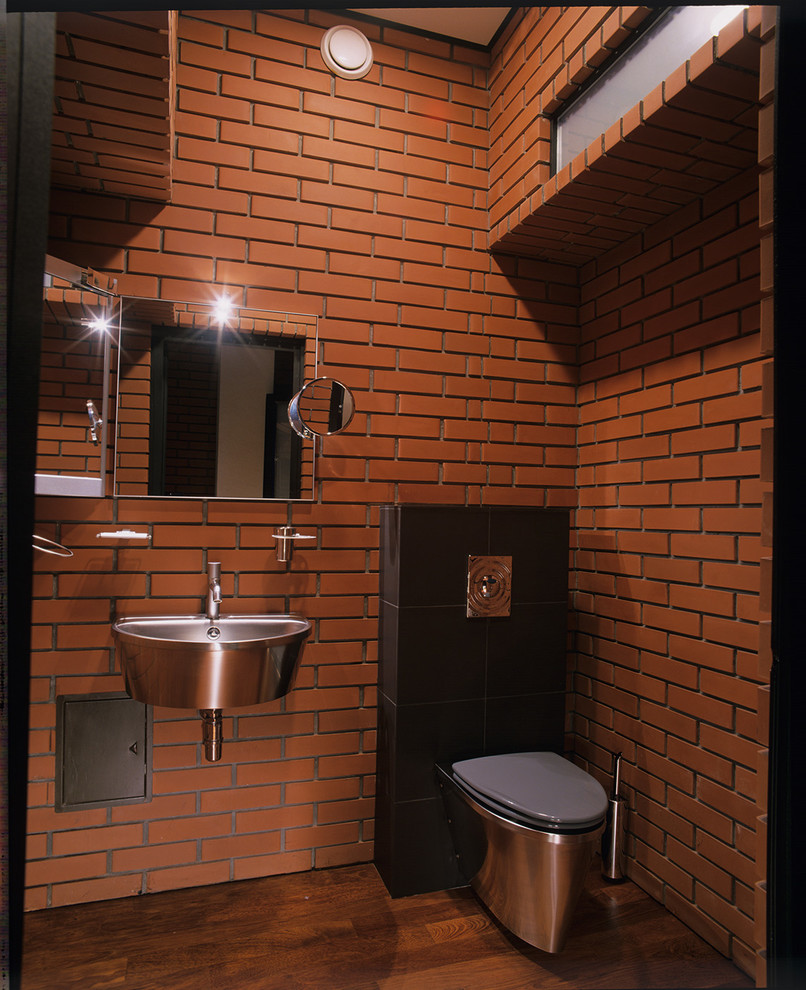Idee per un bagno di servizio contemporaneo di medie dimensioni con piastrelle rosse, pareti marroni, pavimento in legno verniciato, WC a due pezzi, lavabo sospeso e pavimento marrone