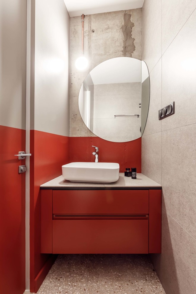 На фото: туалет в современном стиле с плоскими фасадами, оранжевыми фасадами, полом из терраццо, настольной раковиной, серым полом и белой столешницей с