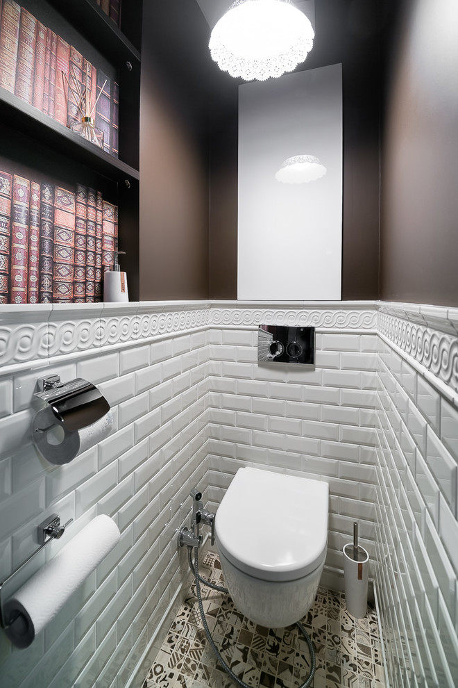 Exempel på ett litet klassiskt toalett, med släta luckor, vita skåp, en vägghängd toalettstol, vit kakel, tunnelbanekakel, bruna väggar, klinkergolv i porslin och flerfärgat golv