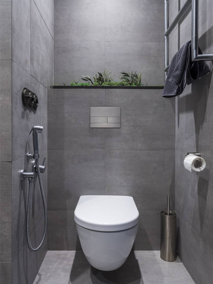 Foto di un bagno di servizio industriale con WC sospeso, piastrelle grigie e pavimento grigio