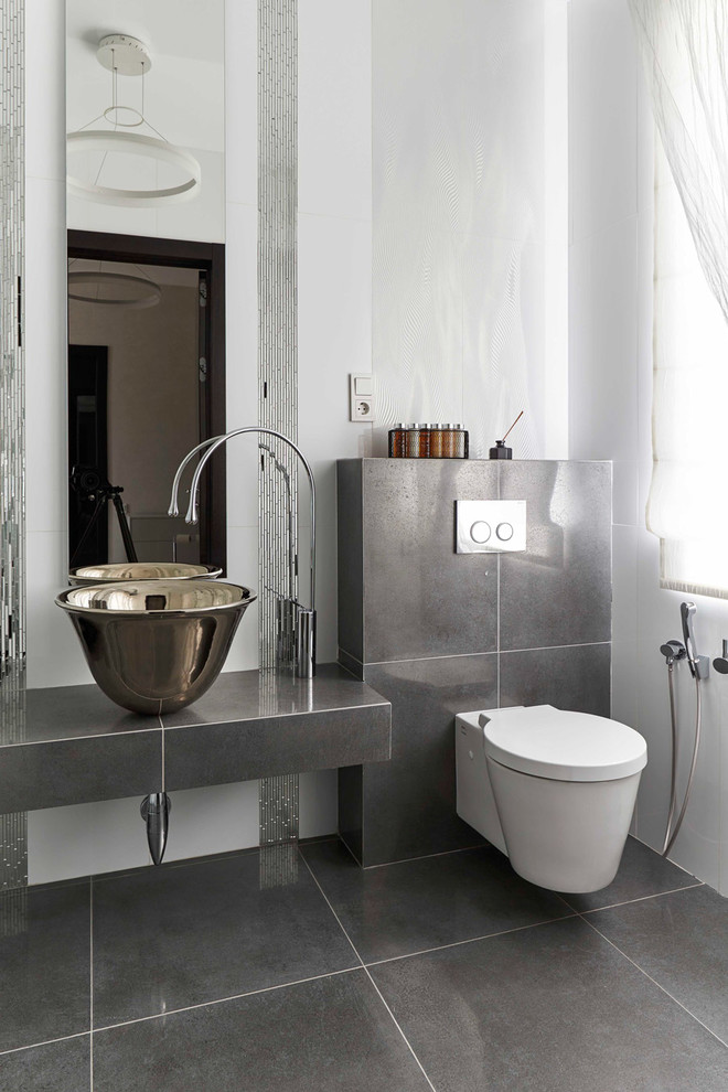 Immagine di un bagno di servizio minimal con WC sospeso, pareti bianche e pavimento grigio