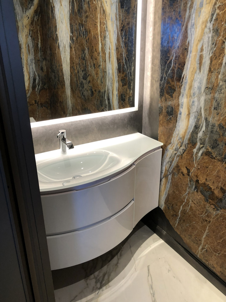 Small contemporary cloakroom in Miami with flat-panel cabinets, white cabinets, a one-piece toilet, brown tiles, marble tiles, brown walls, porcelain flooring, an integrated sink, glass worktops, white floors and white worktops.