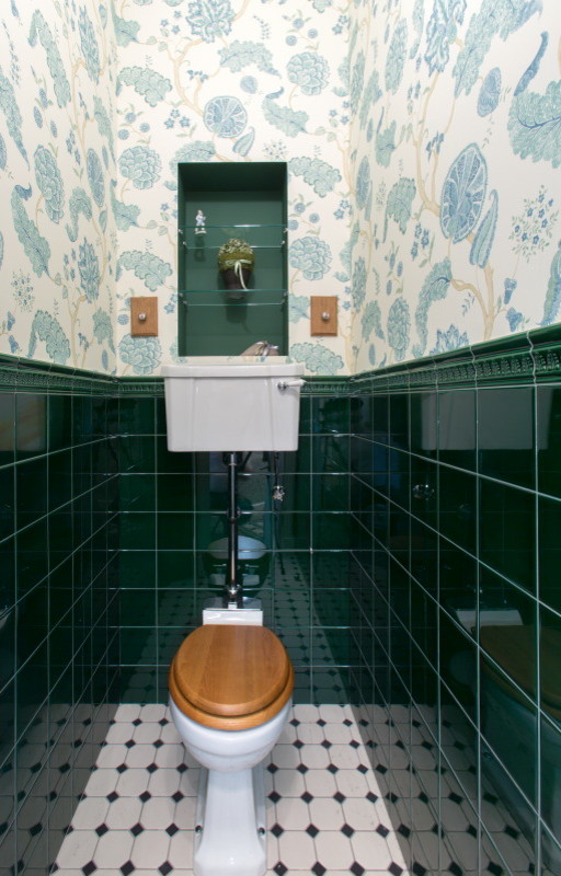 Klassisk inredning av ett litet toalett, med en toalettstol med hel cisternkåpa, grön kakel, keramikplattor, flerfärgade väggar och klinkergolv i porslin