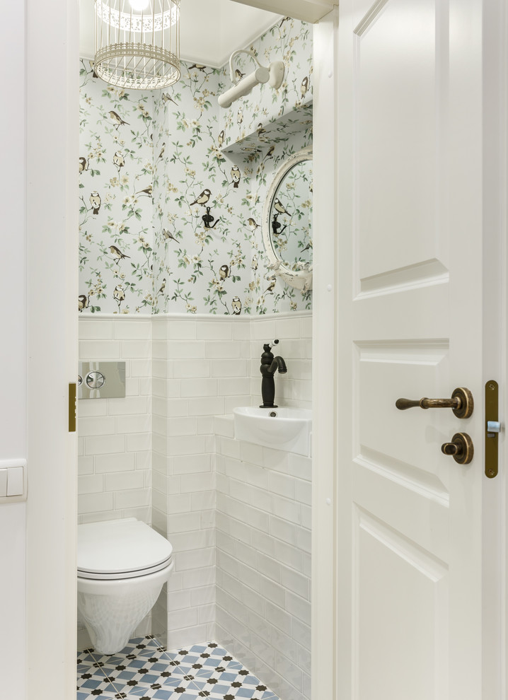 Nordisk inredning av ett toalett, med en vägghängd toalettstol, ett nedsänkt handfat, vit kakel, flerfärgade väggar och flerfärgat golv
