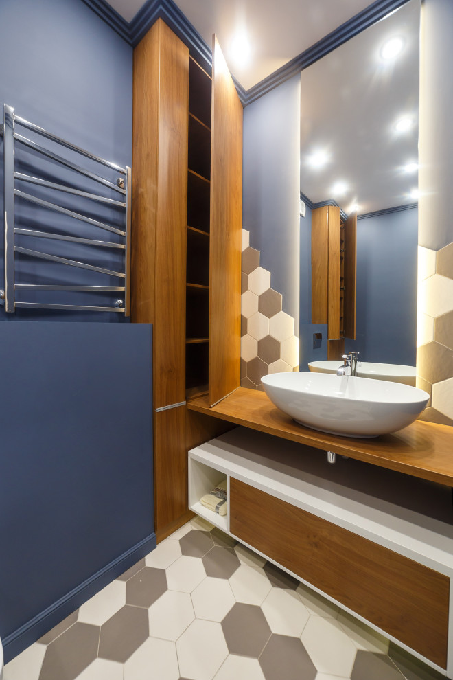 Diseño de aseo actual con armarios con paneles lisos, puertas de armario marrones, paredes azules, lavabo sobreencimera, suelo multicolor y encimeras marrones