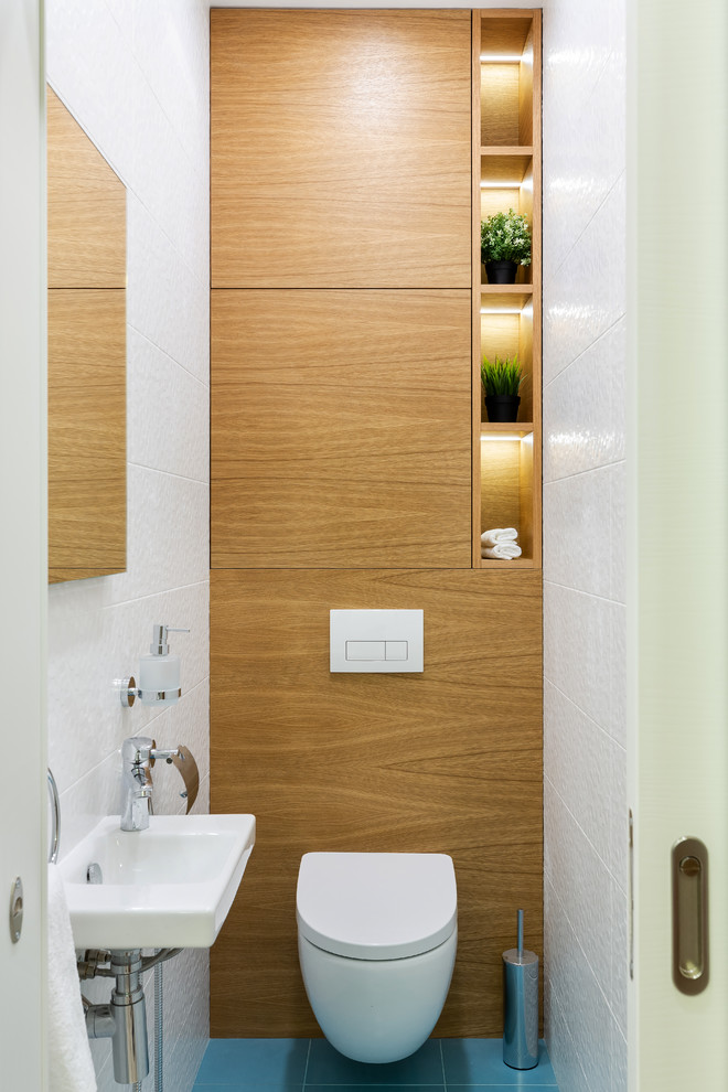Exempel på ett modernt toalett, med släta luckor, skåp i mellenmörkt trä, en vägghängd toalettstol, vit kakel, keramikplattor, klinkergolv i keramik, ett väggmonterat handfat och turkost golv