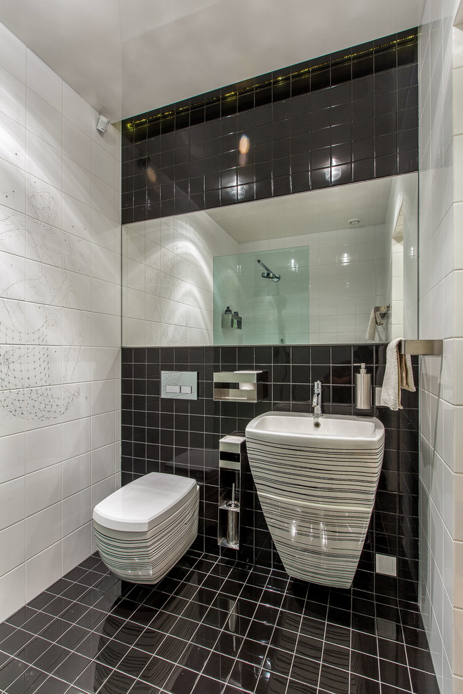 На фото: туалет в современном стиле с инсталляцией, белой плиткой, черной плиткой, разноцветными стенами, раковиной с пьедесталом и черным полом