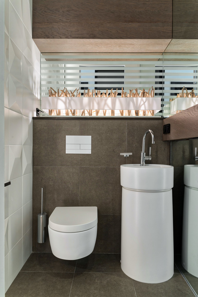 Inspiration för mellanstora moderna toaletter, med en vägghängd toalettstol, vit kakel, brun kakel, keramikplattor, klinkergolv i porslin, ett integrerad handfat och brunt golv