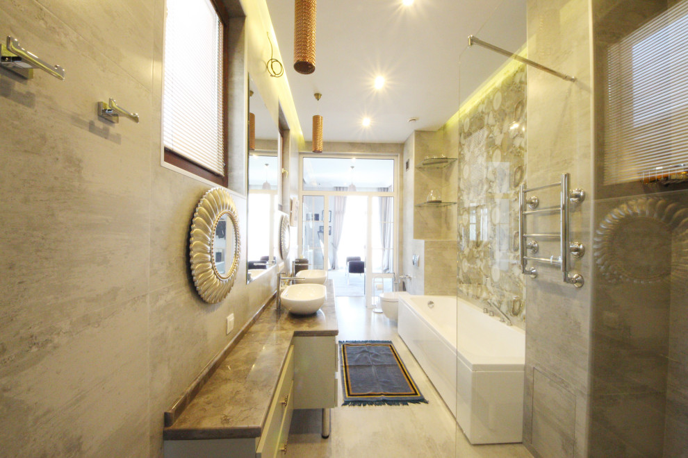 Inredning av ett eklektiskt stort brun brunt toalett, med släta luckor, vita skåp, en vägghängd toalettstol, vit kakel, porslinskakel, grå väggar, klinkergolv i keramik, ett fristående handfat, marmorbänkskiva och grått golv