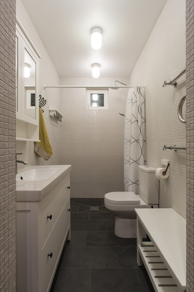 Ispirazione per un bagno di servizio design di medie dimensioni con ante bianche, WC monopezzo, piastrelle bianche, piastrelle a mosaico, pareti bianche, pavimento in ardesia, lavabo da incasso e pavimento nero