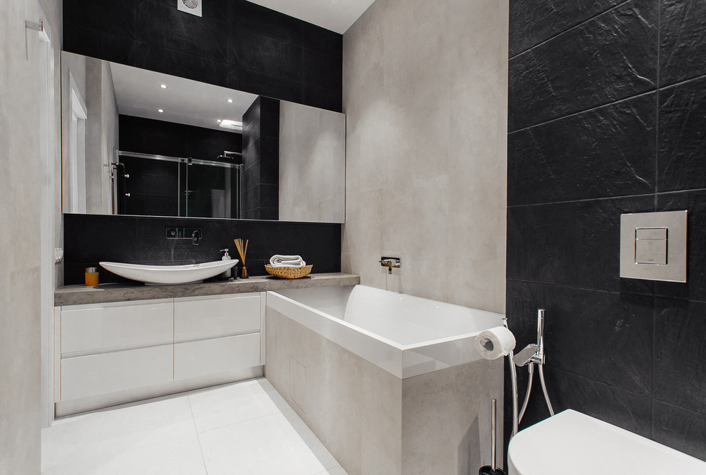 Immagine di un piccolo bagno di servizio bohémian con pareti grigie, pavimento con piastrelle in ceramica, ante lisce, ante bianche, WC sospeso, piastrelle nere, piastrelle in ceramica, lavabo da incasso e top in cemento