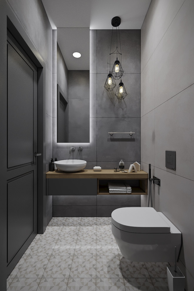 Inspiration for a small contemporary cloakroom in Moscow with flat-panel cabinets, grey cabinets, a wall mounted toilet, grey tiles, porcelain tiles, grey walls, porcelain flooring, a vessel sink, wooden worktops, brown floors and brown worktops.
