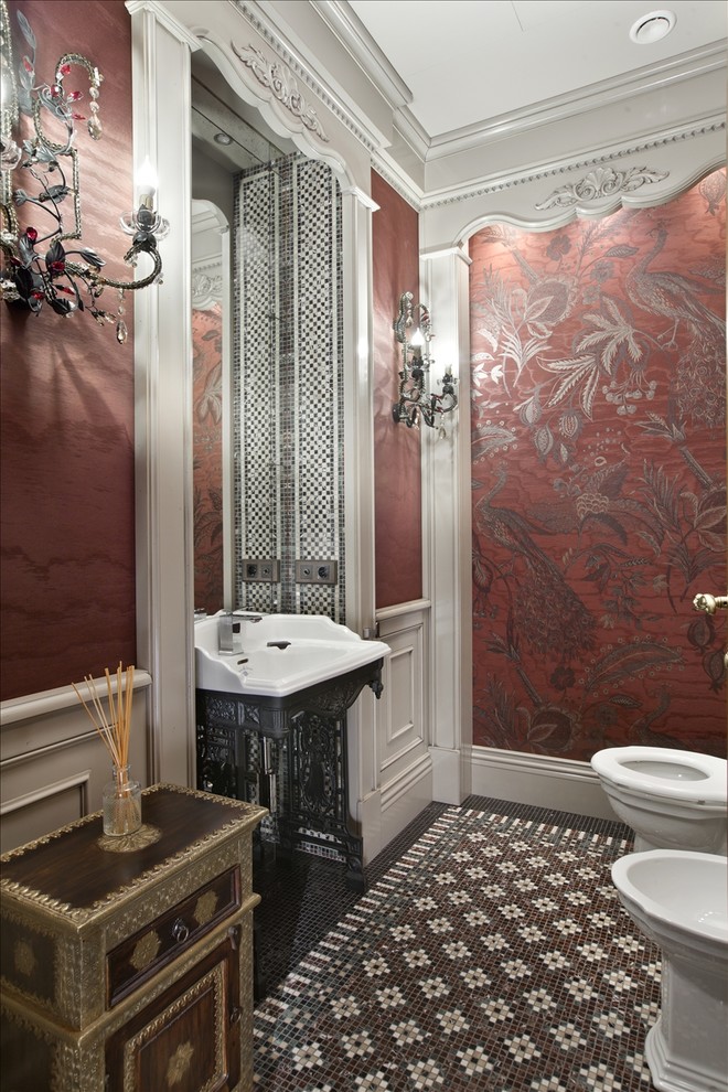 Diseño de aseo clásico con sanitario de dos piezas, suelo con mosaicos de baldosas, lavabo tipo consola, paredes rojas y suelo multicolor