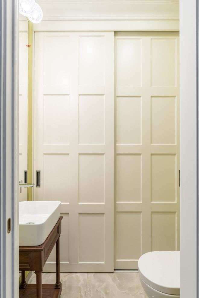 Diseño de aseo tradicional pequeño con armarios con paneles empotrados, puertas de armario blancas, sanitario de una pieza, paredes verdes, suelo de baldosas de porcelana, lavabo con pedestal y suelo beige