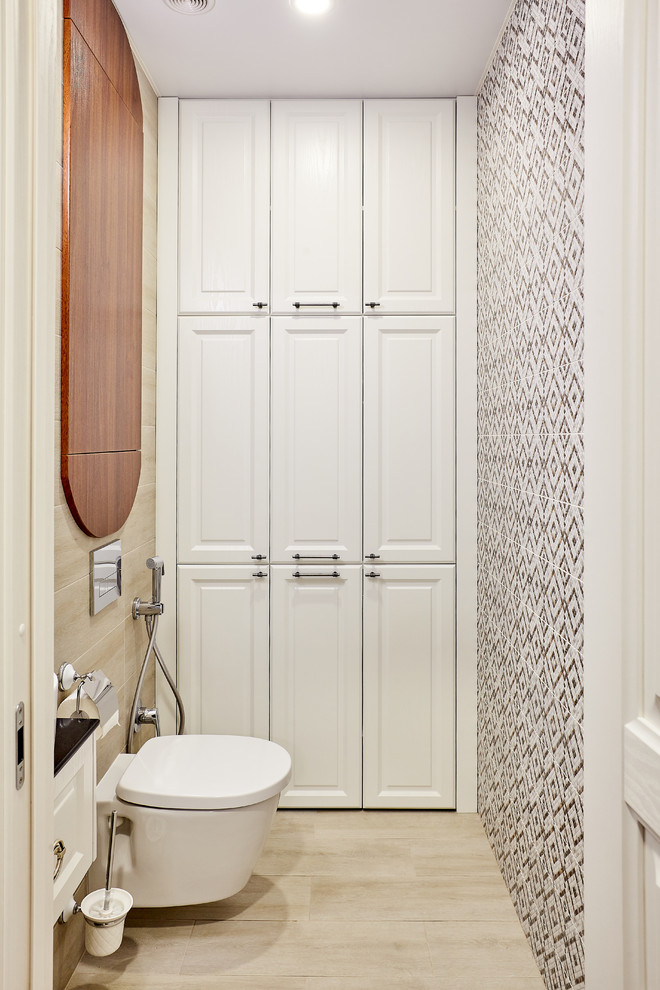 Cette image montre un WC suspendu design avec un placard avec porte à panneau surélevé, des portes de placard blanches, un sol beige, un carrelage noir et blanc et un plan de toilette noir.
