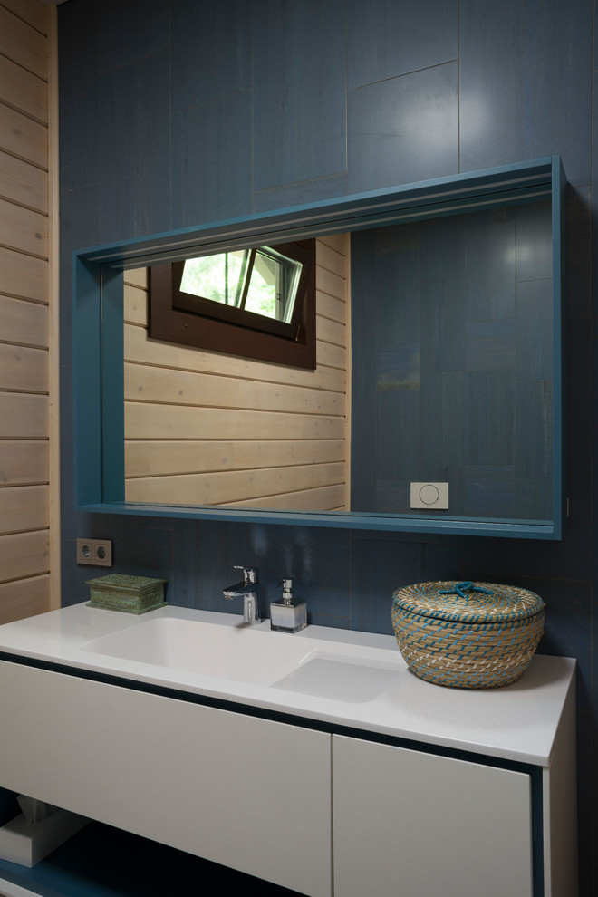 На фото: большой туалет в современном стиле с белыми фасадами, синей плиткой, керамогранитной плиткой, бежевыми стенами, полом из керамогранита, столешницей из искусственного камня, синим полом, плоскими фасадами и монолитной раковиной с