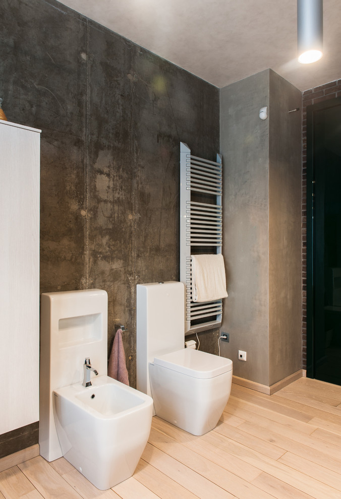 На фото: туалет в стиле лофт с плоскими фасадами, белыми фасадами, биде, серыми стенами, светлым паркетным полом и бежевым полом