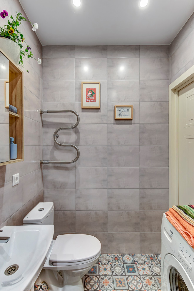 Foto på ett litet funkis toalett, med grå kakel, keramikplattor, klinkergolv i porslin, ett piedestal handfat och flerfärgat golv