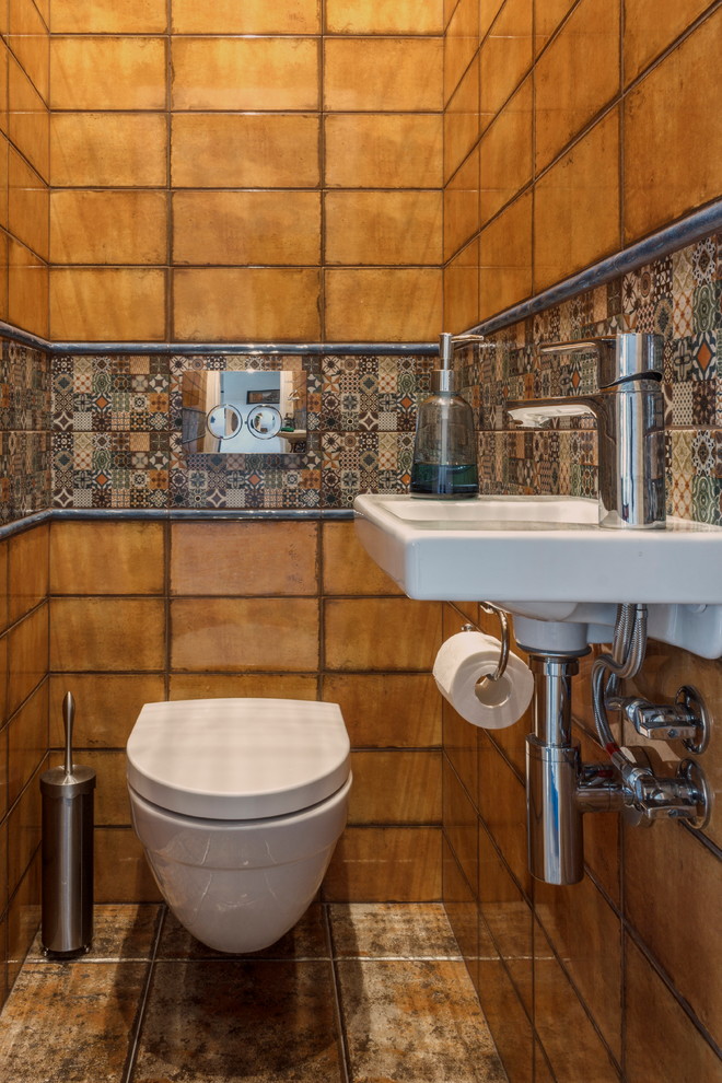 Пример оригинального дизайна: маленький туалет в стиле фьюжн с инсталляцией, оранжевой плиткой, керамической плиткой, полом из керамической плитки, подвесной раковиной и разноцветным полом для на участке и в саду