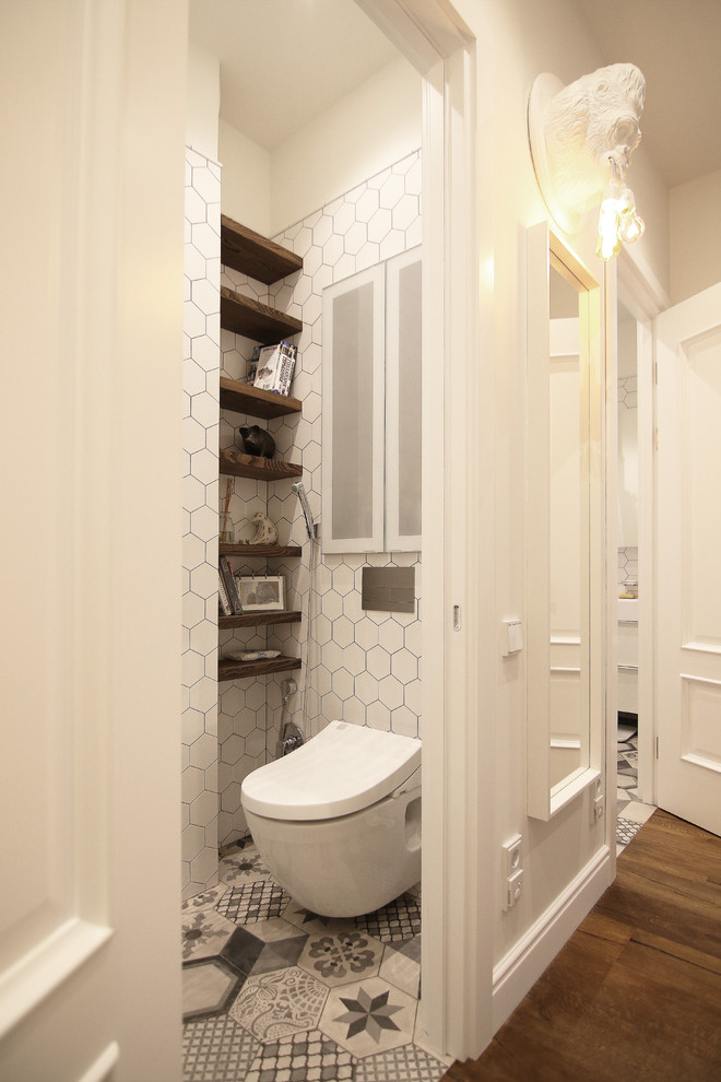 Foto på ett litet minimalistiskt toalett, med släta luckor, en vägghängd toalettstol, vita väggar, klinkergolv i keramik, ett integrerad handfat och grått golv