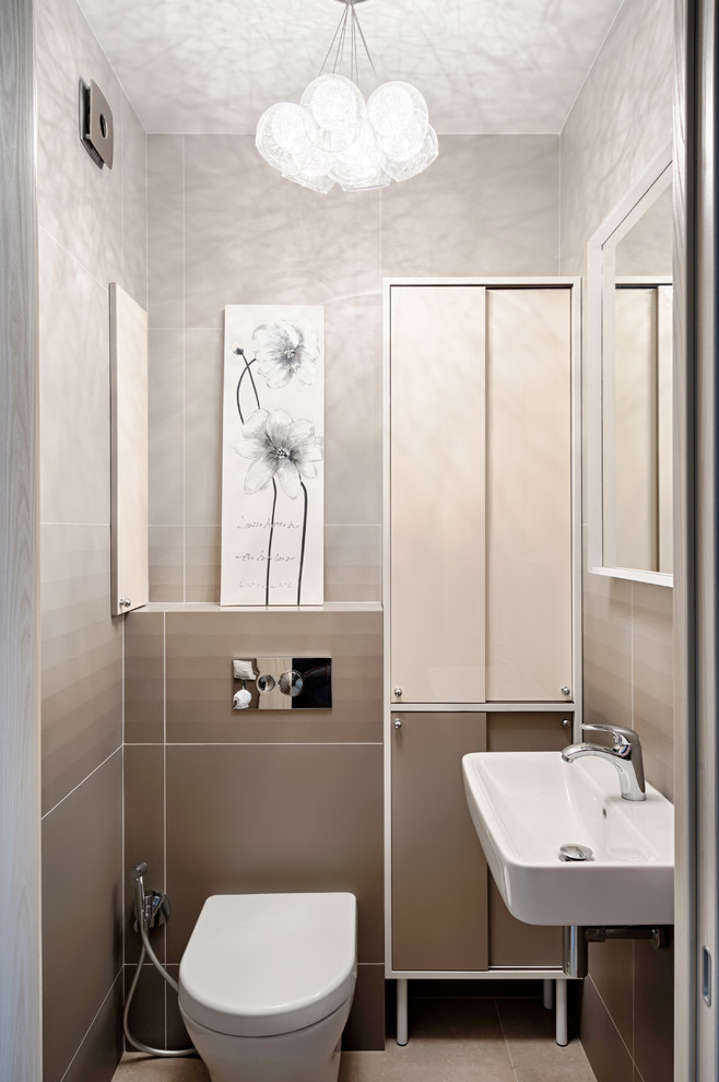 Foto di un bagno di servizio minimal di medie dimensioni con ante lisce, ante beige, WC sospeso, piastrelle beige, pareti beige, pavimento in gres porcellanato, lavabo sospeso e pavimento beige
