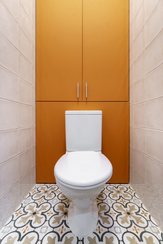 На фото: маленький туалет в современном стиле с плоскими фасадами, оранжевыми фасадами, унитазом-моноблоком, белой плиткой, керамической плиткой, белыми стенами, полом из керамической плитки и разноцветным полом для на участке и в саду
