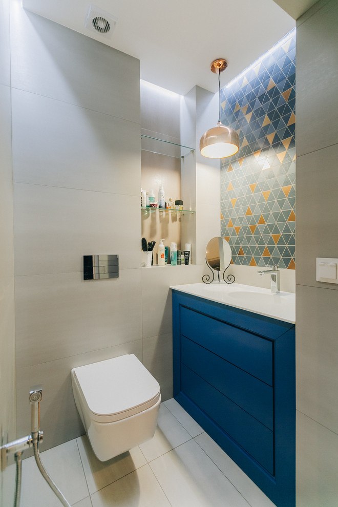 Small transitional beige tile and ceramic tile ceramic tile and beige floor powder room photo in Other with flat-panel cabinets, blue cabinets, a wall-mount toilet, blue walls, an undermount sink, solid surface countertops and white countertops
