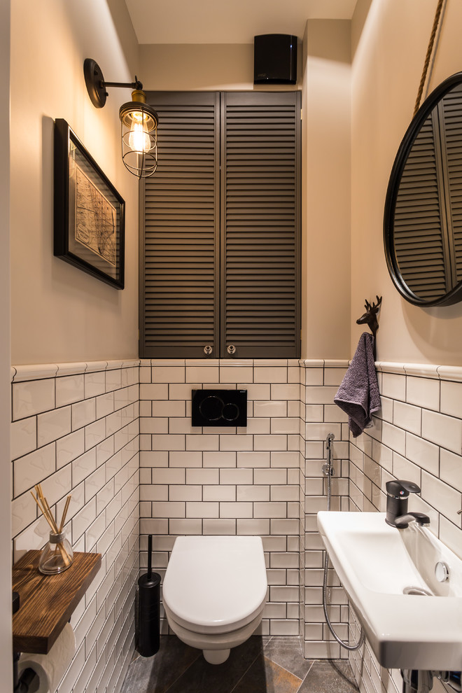 Пример оригинального дизайна: туалет в стиле лофт с инсталляцией, белой плиткой, бежевыми стенами, подвесной раковиной и серым полом