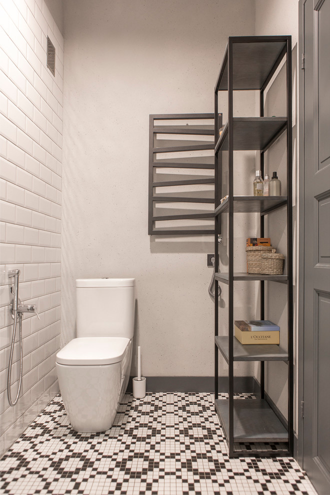 Idéer för industriella toaletter, med en toalettstol med separat cisternkåpa, vit kakel, svart kakel, tunnelbanekakel, vita väggar, mosaikgolv och flerfärgat golv