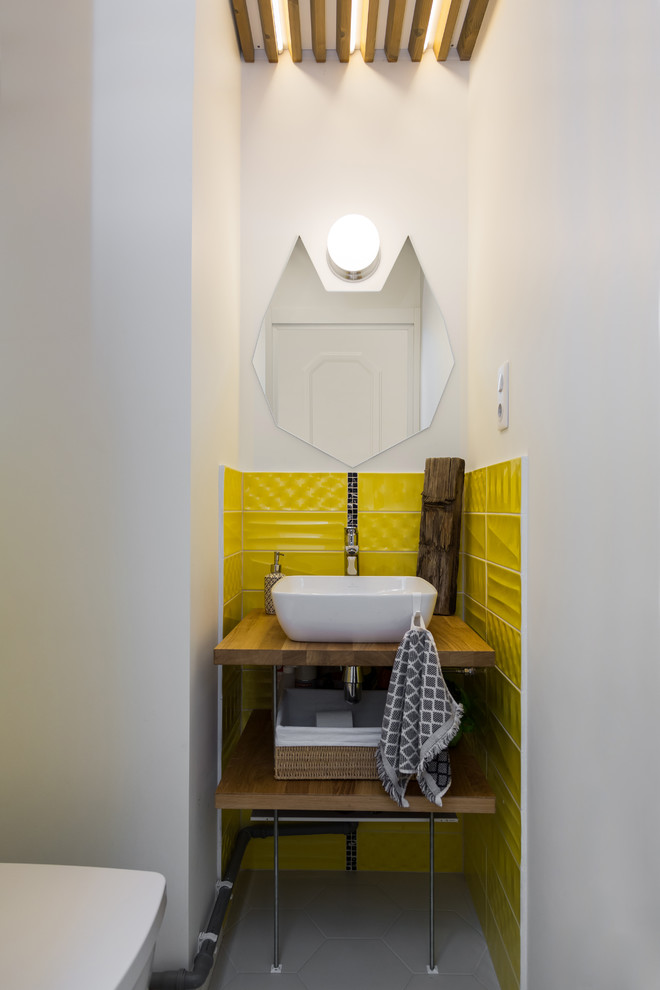 Diseño de aseo escandinavo, pequeño, con armarios abiertos, baldosas y/o azulejos amarillos, paredes blancas, encimera de madera, suelo gris, lavabo sobreencimera y encimeras marrones