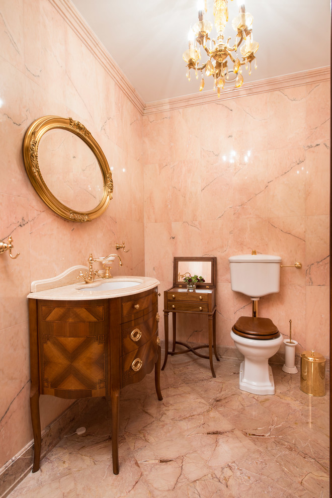 Mittelgroße Klassische Gästetoilette mit rosa Fliesen, Steinfliesen, Marmorboden, hellbraunen Holzschränken, Wandtoilette mit Spülkasten, Unterbauwaschbecken und beigem Boden in Moskau