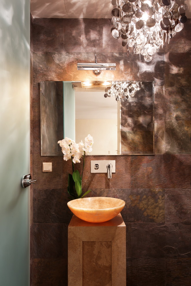 Cette image montre un petit WC et toilettes design avec un carrelage marron, un mur marron, une vasque et un carrelage de pierre.