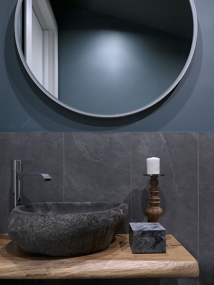 Modern inredning av ett litet beige beige toalett, med svart kakel, porslinskakel, svarta väggar, klinkergolv i porslin, ett fristående handfat, träbänkskiva och svart golv