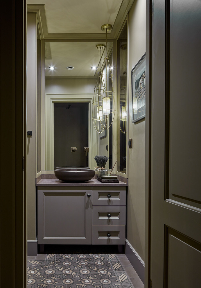 Klassisk inredning av ett litet toalett, med luckor med infälld panel, grå skåp, gröna väggar, mosaikgolv, marmorbänkskiva, ett fristående handfat och grått golv