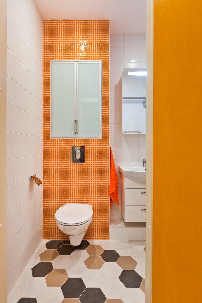 Immagine di un piccolo bagno di servizio minimal con WC sospeso, piastrelle arancioni, piastrelle a mosaico e pavimento con piastrelle in ceramica