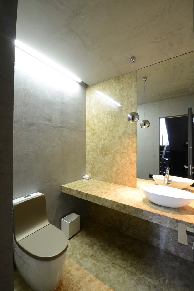 Esempio di un bagno di servizio minimal di medie dimensioni con WC monopezzo, piastrelle gialle, piastrelle di marmo, pareti grigie, pavimento in marmo, lavabo a bacinella, top in marmo e pavimento giallo