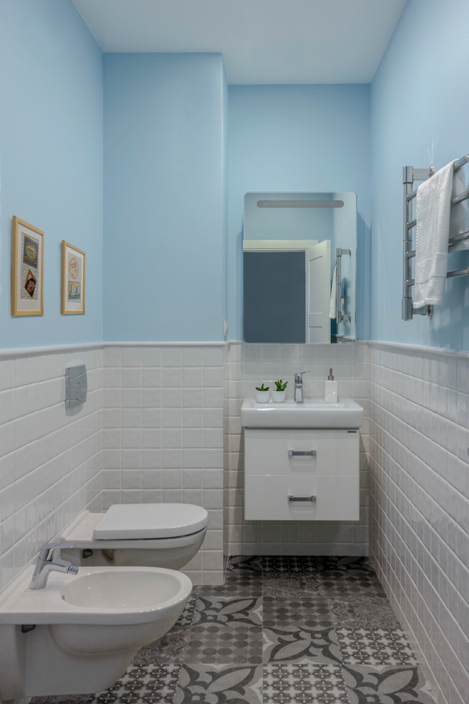 На фото: туалет в современном стиле с плоскими фасадами, белыми фасадами, биде, белой плиткой, серой плиткой, синими стенами и монолитной раковиной с