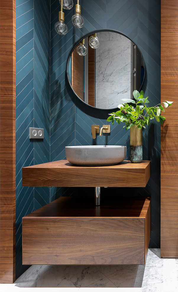 Idée de décoration pour un WC et toilettes design en bois brun avec un placard à porte plane, un sol en marbre, une vasque, un plan de toilette en bois, un sol blanc et un plan de toilette marron.