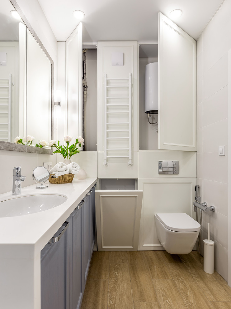 Foto på ett funkis toalett, med grå skåp, en vägghängd toalettstol och ett undermonterad handfat