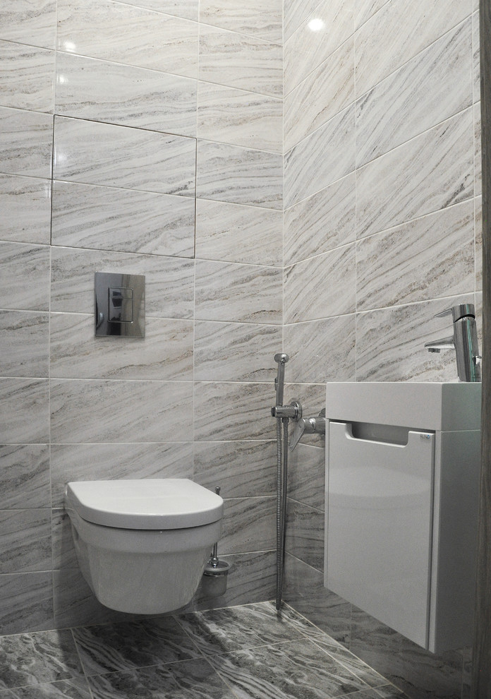 Foto di un piccolo bagno di servizio minimal con ante lisce, ante bianche, WC sospeso, piastrelle grigie, piastrelle in ceramica, pavimento con piastrelle in ceramica, lavabo sospeso e pavimento grigio