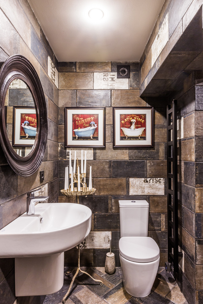 Imagen de aseo rústico con baldosas y/o azulejos marrones, lavabo suspendido, suelo marrón, sanitario de dos piezas y paredes multicolor