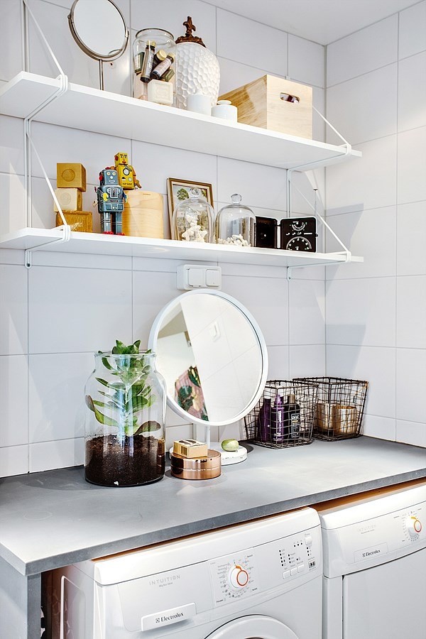 Bild på en minimalistisk linjär liten tvättstuga, med öppna hyllor, bänkskiva i betong, vita väggar och tvättmaskin och torktumlare byggt in i ett skåp