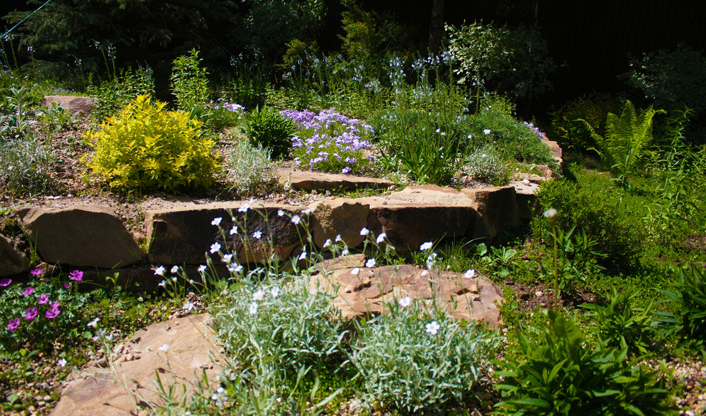 Exempel på en stor skandinavisk trädgård i full sol som tål torka, dekorationssten och i slänt på våren, med marksten i tegel