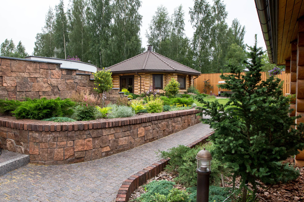 На фото: летний участок и сад в современном стиле с подпорной стенкой с
