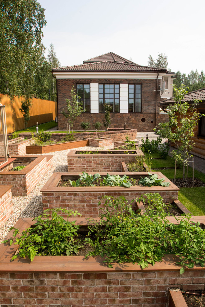 Klassisk inredning av en trädgård i full sol, med en köksträdgård och grus på sommaren
