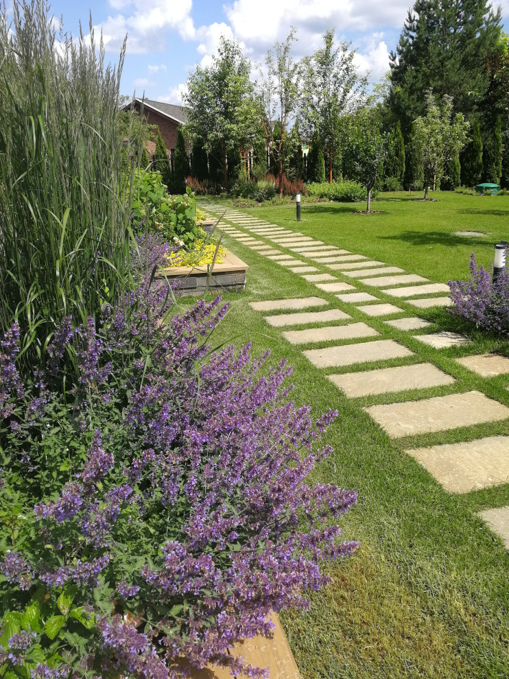 На фото: солнечный, летний регулярный сад среднего размера на заднем дворе в современном стиле с дорожками, хорошей освещенностью и покрытием из каменной брусчатки